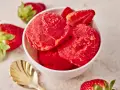 Schüssel mit erfrischendem Erdbeer Sorbet, garniert mit frischen Erdbeeren und einer goldenen Löffel.