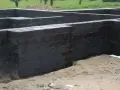 Fundament betonowy z czarnym abizolem, gotowy na kolejne etapy budowy.