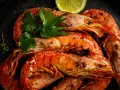 Gambones a la plancha, jugosos y dorados, servidos con perejil fresco y rodajas de lima. ¡Un manjar irresistible!