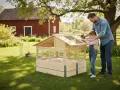 Pappa och dotter bygger en kaninbur utomhus. En kanin sitter i en annan bur i bakgrunden.