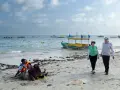 Spacerowery na plaży w Somalii, z łodziami na morzu. Czy Somalia jest bezpieczna? Turyści spacerują, podczas gdy lokalni mieszkańcy odpoczywają na piasku.