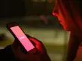 Dziewczyna patrzy na ekran telefonu z logo Tindera. Zastanawia się, co odpisać na "czego szukasz na Tinderze?".