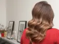 Kobieta z pięknymi, falowanymi włosami w odcieniu sombre jasny brąz. Delikatne refleksy dodają im blasku.