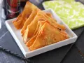 Wontons fritos dorados y crujientes en un plato blanco.