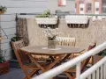 Holztisch mit Stühlen und Gänseblümchen, Wandregal mit Pflanzen, schöne Balkon Ideen für Ihr Zuhause.