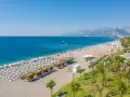 Piękna plaża z rzędami leżaków i parasoli, gdzie jest Antalya. Błękitne morze i góry w tle tworzą idealny krajobraz.