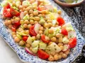 Un'insalata di legumi colorata e fresca con ceci, pomodorini, cetrioli e ravanelli, condita con erbe aromatiche.