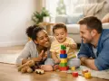 Glückliche Familie spielt mit Bauklötzen. Das Kind lernt spielerisch, wie man spricht, während Mama und Papa zuschauen.