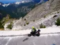 Motociclista in abbigliamento giallo fluo affronta il passo del vestito, tra cave di marmo e montagne imponenti.