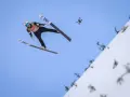 Skoczek narciarski w locie, z dronem w tle. Zastanawiasz się, ile waży skoczek narciarski, by osiągnąć taką odległość?