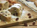 Stollen formen ohne backform: saftige Stollenstücke mit Rosinen und Puderzucker auf Holzbrett, umgeben von Nüssen und Trockenfrüchten.