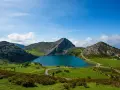 Lago azul rodeado de montañas verdes y caminos sinuosos, parte de la red de parques nacionales.