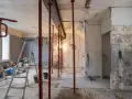 Chantier en cours : étais rouges soutenant un linteau, murs abattus, échelle et matériaux. Préparation pour une ouverture mur porteur.