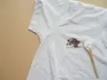 Tache sur t-shirt blanc après lavage, avec une cuillère de poudre blanche à côté.