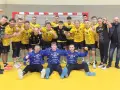 Drużyna KSSPR Końskie świętuje zwycięstwo. Zawodnicy w żółtych i niebieskich strojach pozują do wspólnego zdjęcia na boisku.