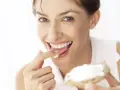 Une femme savoure une bouchée de pain avec de la saint agur crème enceinte, un sourire aux lèvres.