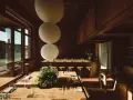 Gemütliches Restaurant in **Aerde Berlin** mit Holztischen, großen Papierlampen und Blick auf das Wasser.