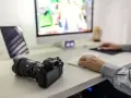 Aparat fotograficzny i tablet na biurku, obok komputera. Ułatwia to proces, jak przegrać zdjęcia z telefonu na komputer.