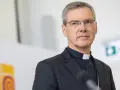 Ein Bischof mit Brille und Soutane spricht in ein Mikrofon. Die Frage "wer bezahlt den Bischof" wird hier nicht beantwortet, aber das Bild zeigt ihn bei einer öffentlichen Rede.