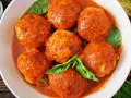 Polpette di pane succulente in salsa di pomodoro, guarnite con foglie di basilico fresco. Un piatto che sa di casa.
