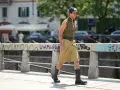 Uomo con un elegante outfit sportivo estivo: gilet a fantasia, bermuda color sabbia e stivali.