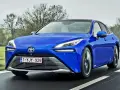 Niebieska Toyota Mirai jedzie po drodze. Sprawdź aktualną toyota mirai cena i dowiedz się więcej o tym innowacyjnym samochodzie.