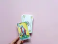 Mano sostiene la carta "El Mago" de un tarot del amor presente pasado y futuro.
