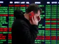 Hombre preocupado habla por teléfono frente a pantalla de bolsa de valores de Nueva York, con números rojos y verdes indicando un posible crack.