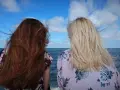 Dwie kobiety z wiatrem we włosach, jedna z rudymi, druga z blond włosami. Zastanawiają się, jak rozjaśnić ciemne włosy farbowane.