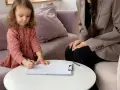 Mała dziewczynka rysuje, podczas gdy psycholog obserwuje. Proces ten może być częścią diagnozy ados.