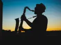 Sylwetka muzyka w kapeluszu grającego na saksofonie o zachodzie słońca. Prawdziwy mistrz, jeden z najlepszych bluesmanów świata.