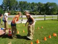 Des collègues s'amusent lors de jeux entre collègues de travail, sautant dans des sacs en toile de jute sur une pelouse verte.