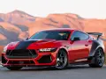 Czerwony mustang shelby z czarnymi pasami i spojlerem na tle pustynnych gór.