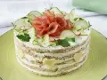Herzhafter Kuchen mit Schichten aus Brot, Frischkäse, Gurken und Schinken. Dekoriert mit Radieschen, Kräutern und Käseherzen.