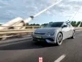 Szary Kia EV6 jedzie po moście w słoneczny dzień.