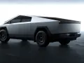 Futurystyczny Tesla Cybertruck w kolorze srebrnym, z ostrymi krawędziami i masywnymi kołami, prezentuje się na ciemnej, betonowej podłodze.