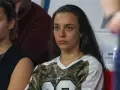 Natalia Padilla Bidas, zamyślona, siedzi na trybunach w koszulce z motywem kamuflażu.