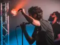 Ein Sänger mit Mikrofon auf einer Bühne, umgeben von Bühnenlichtern. Das ist, was Indie-Musik ausmacht: Leidenschaft und Energie.