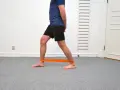 Man tränar för att stärka stela fotleder med ett orange träningsband runt anklarna.