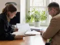 Prawniczka w todze przegląda dokumenty z klientem. Czas na złożenie wniosku o nadanie klauzuli wykonalności.