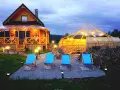 Drewniany domek z werandą, jacuzzi pod zadaszeniem i leżakami w malowniczej okolicy.