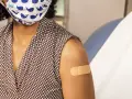 Osoba w maseczce z wielorybami ma plaster na ramieniu po szczepieniu. Dbanie o zdrowie, w tym szczepionka HPV, to ważny krok.