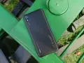 Czarny telefon Xiaomi Redmi 7 leży na zielonej, metalowej ławce.