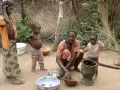 Dzieci i matka w tradycyjnej chacie w Burkina Faso. Kobieta przygotowuje posiłek, a dzieci obserwują.