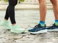 Två par löparskor, mintgröna Asics Gel Luminus 2 dam och mörkblå herrskor, står på stenar vid en flod.