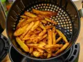 Złociste frytki w koszyku frytkownicy beztłuszczowej. Tak działa air fryer, przygotowując chrupiące przekąski.