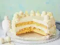 Eine köstliche Piña Colada Torte mit Kokosraspeln und Ananasstücken, verziert mit Sahnetuffs und Pralinen.