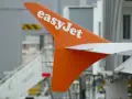 Pomarańczowy statecznik pionowy samolotu easyJet z białym logo, gotowy do przyjęcia bagażu pasażerów.