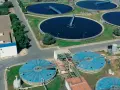 Vista aérea de una planta de depuración de aguas con grandes tanques circulares y estructuras industriales.