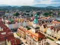Widok z lotu ptaka na kolorowy rynek starego miasta z wieżą ratuszową i górzystym tłem.